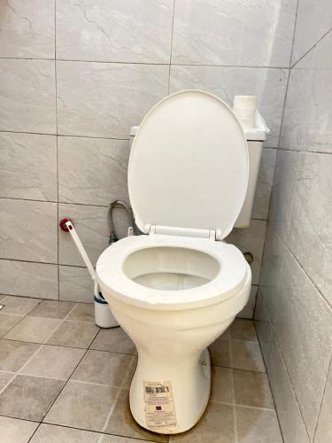 ein weißes WC im Bad mit einer Reinigungsbürste in der Unterkunft P&P homes in Kampala
