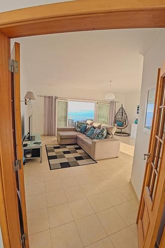 a living room with a couch and a view of the ocean at Ericeira Sunset Apartment in Ericeira