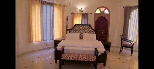 a bedroom with a bed and a chair and windows at Govind Garh Nathdwara in Namano