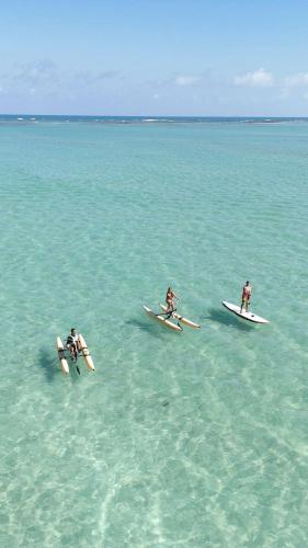 three people are laying on surfboards in the ocean at La Palma Hostel in Maragogi