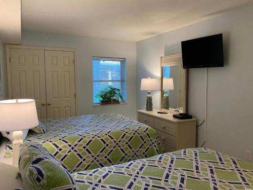 Private Ashworth Resort Direct Oceanfront View New في ميرتل بيتش: غرفة نوم مع سرير وتلفزيون بشاشة مسطحة