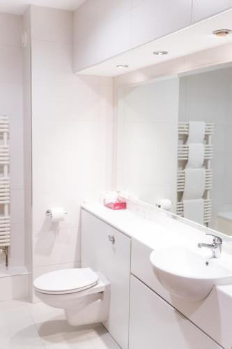 a white bathroom with a toilet and a sink at Lady Gregory Hotel, Leisure Club & Beauty Rooms in Gort