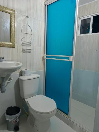 a bathroom with a toilet and a blue shower door at Hospedaje Torices Cartagena in Cartagena de Indias