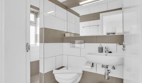 a white bathroom with a toilet and a sink at Apartamentos LIVVO Mar Azul - Adults Only in Corralejo