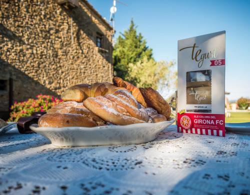Un plato de pan y una caja de rollos de canela sobre una mesa. en Hotel Mas Rabiol -Emporda-Only Adults-Eco Hotel, en Peratallada