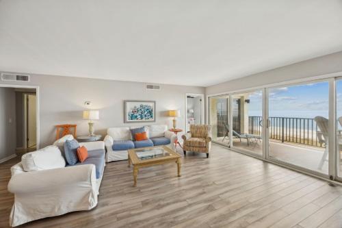 a living room with white furniture and a view of the ocean at Beach Cottage Look Condo, Ocean View from Spacious Balcony in Fernandina Beach