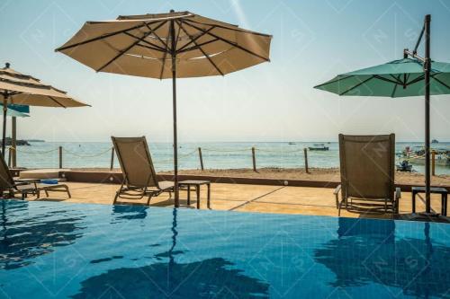 una piscina con sedie e ombrelloni e l'oceano di Luxury Beachfront Condo Punta Mita a Punta Mita