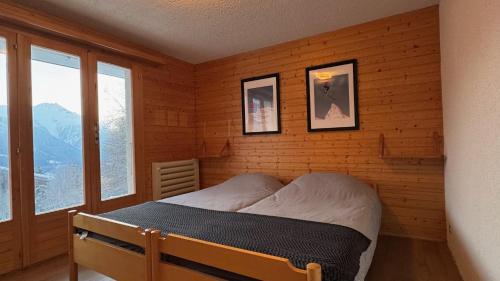 Un dormitorio con una cama en una habitación con ventanas. en Chalet Montis, en Bellwald