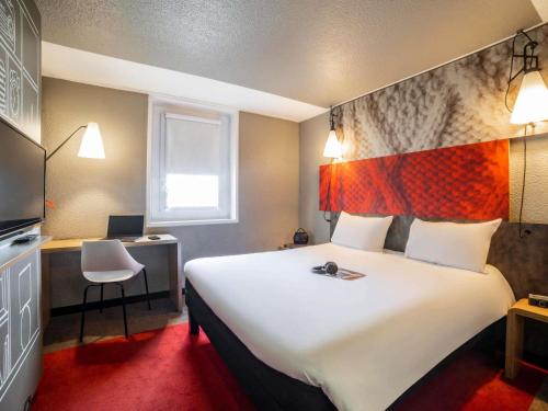 um quarto de hotel com uma cama grande e uma escrivaninha em ibis Paris porte de Bercy em Charenton-le-Pont