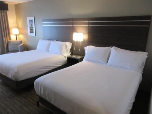two beds in a hotel room with white sheets and pillows at Best Western Champions Forest Inn and Suites in Houston
