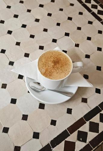 a cup of coffee sitting on a plate on a table at Riad Dar Haven in Tamraght Oufella