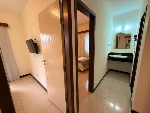 a bathroom with a mirror and a sink at Girassol Praia Hotel in Porto Seguro