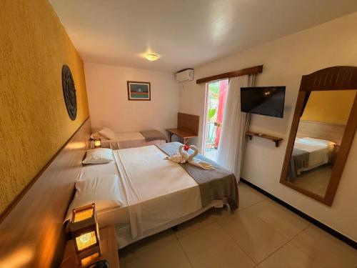 a bedroom with a large bed with a mirror at Girassol Praia Hotel in Porto Seguro
