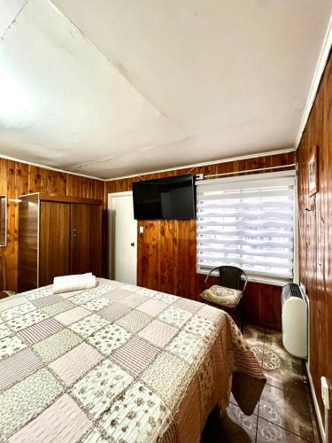 a bedroom with a large bed and a television in it at Hostal Las Heras in Temuco
