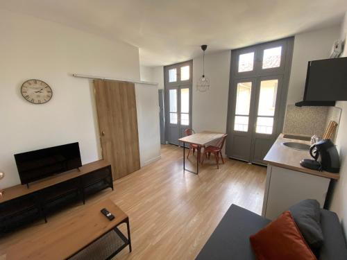 ein Wohnzimmer mit einer Couch und einer Uhr an der Wand in der Unterkunft V3 Studio tout confort plein centre 5 min Golfech in Valence-dʼAgen