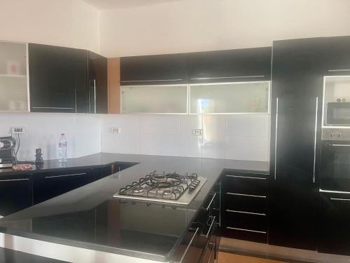 una cucina con mobili neri e un forno a piano cottura di Magnifique villa alliant tradition et modernité en plein oliveraie 