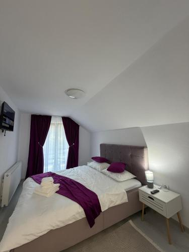 een slaapkamer met een groot bed met paarse kussens bij Casa din lunca 2 in Poiana Mărului