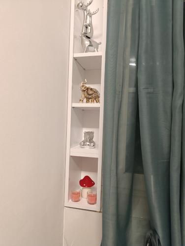 a white book shelf with a green curtain at Studio San in Arandjelovac
