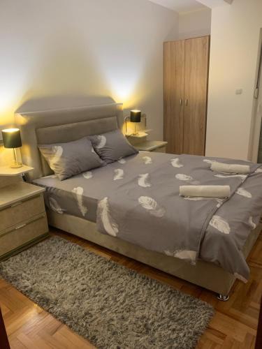 ein Schlafzimmer mit einem Bett mit einer grauen Bettdecke und einem Teppich in der Unterkunft City Comfort Apartment in Vranje