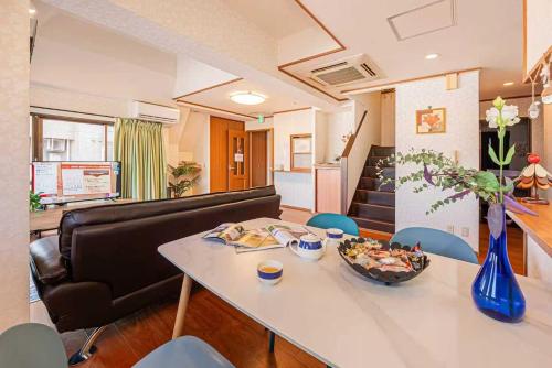 a living room with a couch and a table and chairs at 台東区広々吹き抜けリビングのメゾネットタイプのお家 in Tokyo