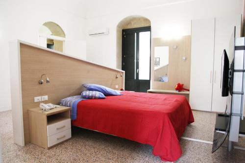 a bedroom with a bed with a red blanket and a mirror at RTA Palazzo Judica in Palazzolo Acreide