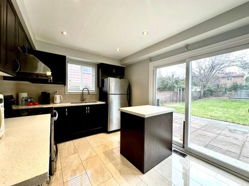 a kitchen with a stainless steel refrigerator and a sliding glass door at Cozy Queen room with Shared Bath near Seneca Finch 404 in Toronto