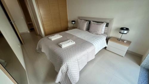 une chambre avec un lit blanc avec deux serviettes dessus dans l'établissement Laguna mar beach house, à Monte Gordo