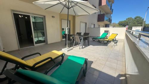 a patio with chairs and tables and an umbrella at Laguna mar beach house in Monte Gordo