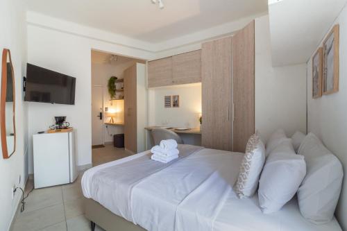 a bedroom with a white bed and a kitchen at 4 minutos da Praia de Copacabana - NSC803 in Rio de Janeiro