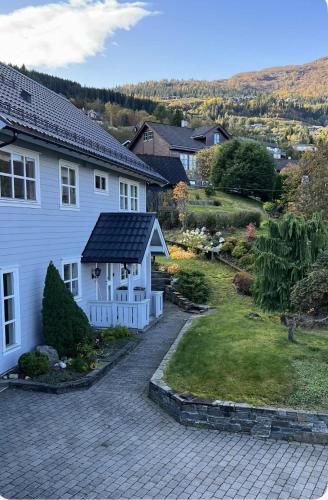 a white house with a garden and a house at Cozy Central Apartment - Free Parking & Wifi in Vossevangen