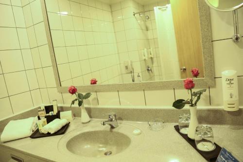 a bathroom with a sink with flowers and a mirror at Swiss Al Hamra Hotel in Dammam