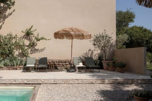 ChampignollesTraditional Apartment In The Heart Of Burgundy的一组椅子和一把遮阳伞,位于游泳池旁