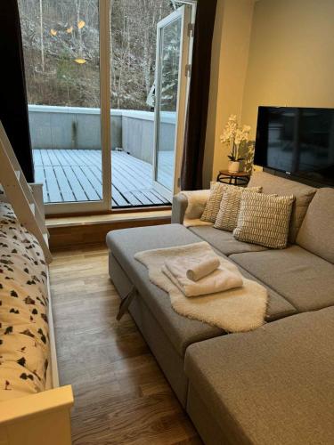 a living room with a couch and a large window at Resort by the Lake - Pool & Sauna in Vossevangen