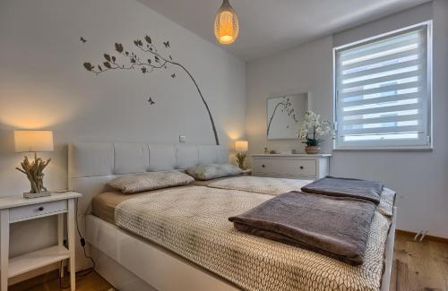 een witte slaapkamer met een groot bed en een raam bij Seaside Apartments in Split