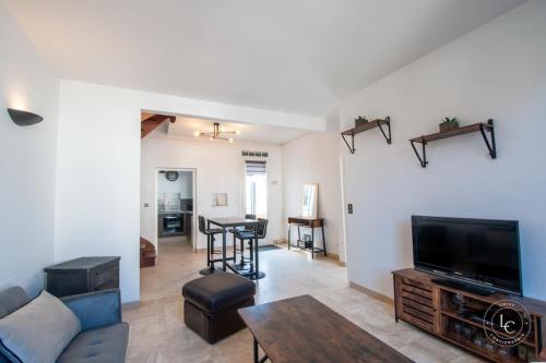 ein Wohnzimmer mit einer Couch, einem Fernseher und einem Tisch in der Unterkunft Maison Le Damier - Proche Center Parcs et Lamotte Beuvron - 3 chambres in La Ferté-Saint-Aubin