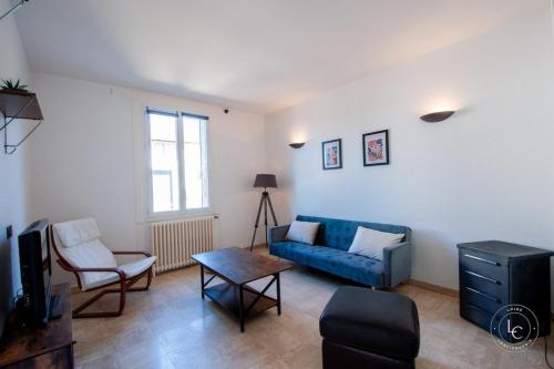 ein Wohnzimmer mit einem blauen Sofa und einem Tisch in der Unterkunft Maison Le Damier - Proche Center Parcs et Lamotte Beuvron - 3 chambres in La Ferté-Saint-Aubin