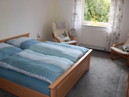una camera da letto con un letto, una sedia e una finestra di Ferienwohnung Feldhofs a Medebach