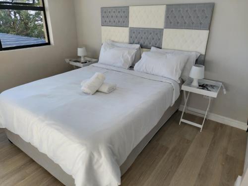 a bedroom with a large white bed with two pillows at Cosmic View Lodge in East London