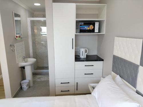 a bedroom with a bed and a bathroom with a sink at Cosmic View Lodge in East London