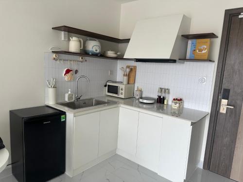 una cucina bianca con un lavello e un forno a microonde di Căn nhà nhỏ a Long Bình