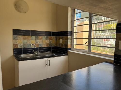a kitchen with a sink and a window at Outspan Lodge in Fish hoek