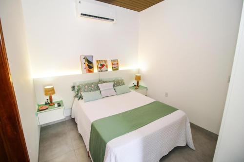 a bedroom with a white bed with a green and white blanket at Flat Aconchego dos Pássaros in Bonito