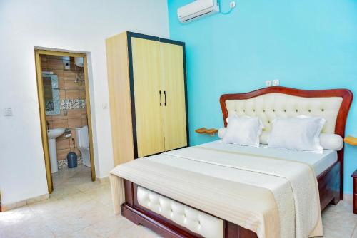 a bedroom with a bed with a blue wall at Milo & Aby Resort, Le Mar in Kribi