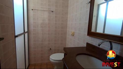 a bathroom with a sink and a toilet and a mirror at Cobertura duplex Bombas in Bombinhas