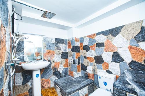 Un baño con lavabo y pared de piedra. en Wow Reef Break, en Dondra West