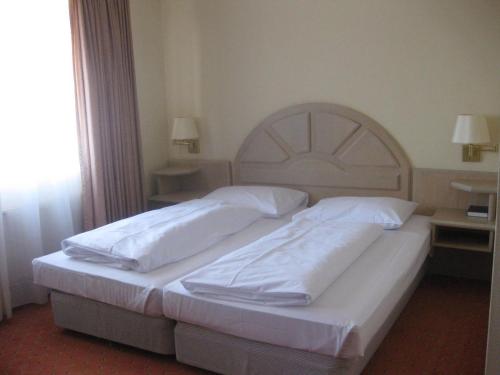 a bedroom with two beds with white sheets at Abakus-Hotel in Sindelfingen