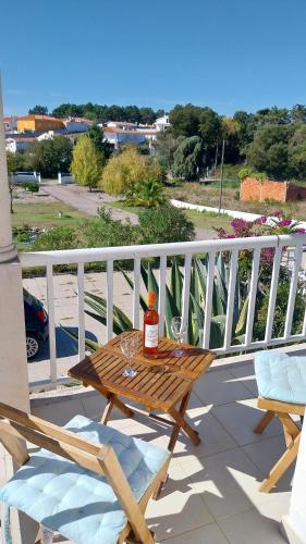 a wooden table on a balcony with a bottle and glasses at Casa da Alegria Boutique Guest Suite in Caldas da Rainha