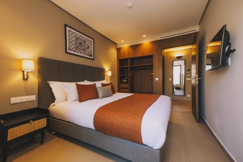 a hotel room with a large bed and a television at Dally Apart Hotel in Rabat