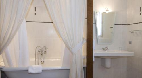 a white bathroom with a tub and a sink at Hotel De France in Mende