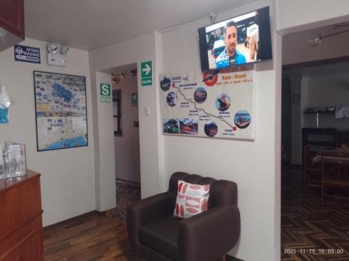 普诺San Antonio的客厅配有椅子和墙上的电视